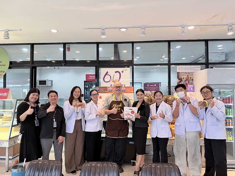 คณะนักศึกษาอุกหนุนขนมปังและถ่ายรูปหมู่กับเจ้าหน้า ศพอ. ที่ร้าน APCD 60+ bakery & Chocolate café.